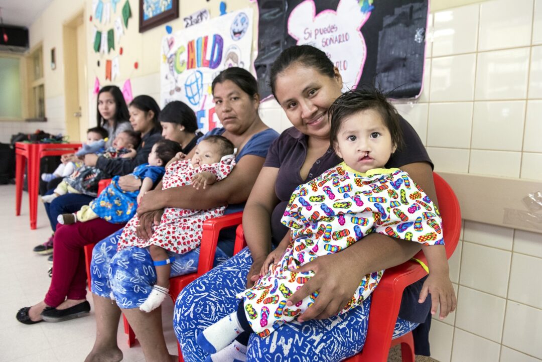 During a 2018 Operation Smile Bolivia surgical programme, Nora and Damian, right, wait for care alongside four other patients and parents. Photo: Margherita Mirabella.