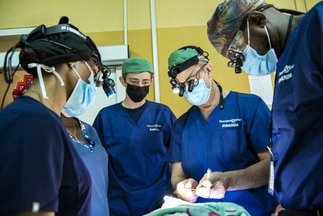 Through training and education opportunities, Operation Smile Rwanda has devoted years to enhancing the capacity of surgical care in the country with its surgical training rotations. Prior to surgery during the 2022 Rwanda surgical programme, Liam Magee, center, watches as his father, Billy, demonstrates a surgical technique to plastic surgery resident Dr. Yves Nezerwa of Rwanda, right. Photo: Margherita Mirabella.