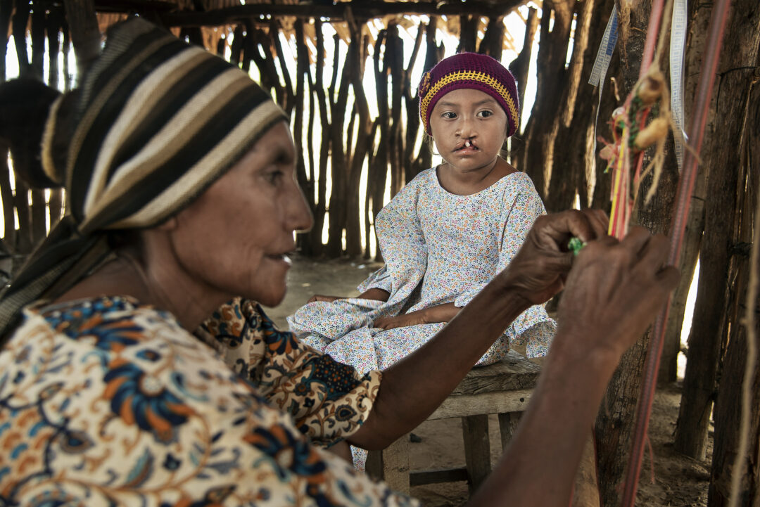Elba weaves a mochila, a traditional Wayuu wool bag, as Lexxi watches.
