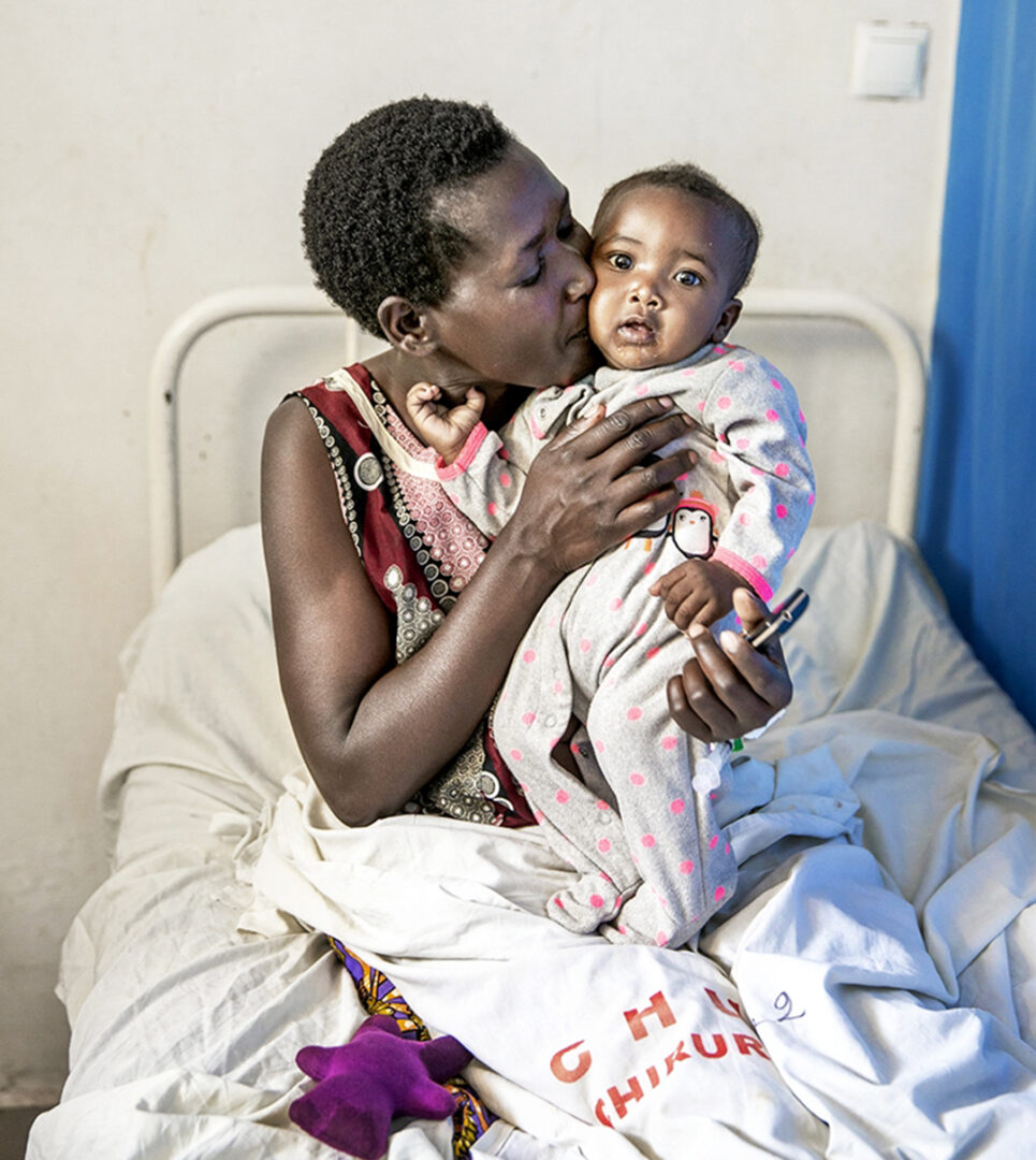 Marthe cuddling her daughter Promesse in a hospital bed. Photo by Jorgen Hildebrandt.