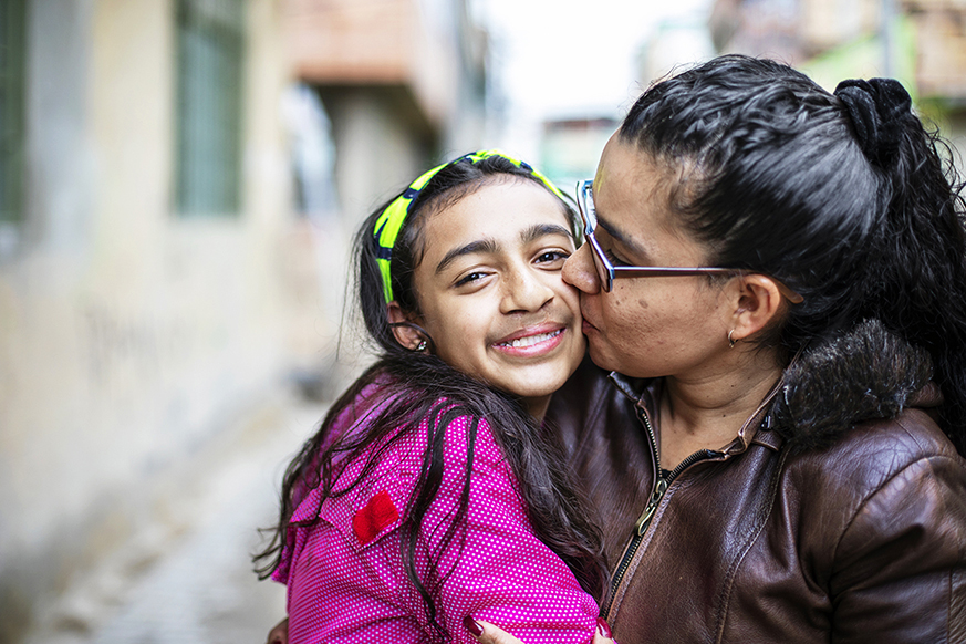 Mum kissing daughter on her cheek